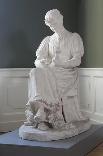 Billedhuggerinde siddende med en statuette i hånden